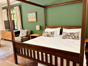 a bedroom with a four poster bed and a chair at Oatlands Cottages in Grahamstown