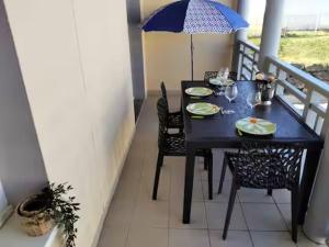 a black table and chairs on a balcony with an umbrella at Studio proche océan dans résidence 3 étoiles avec piscine et parking privé in Mimizan-Plage