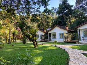 a house with a green yard with a pathway at Pousada Águas do Alto in São Francisco Xavier