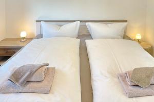 two beds in a bedroom with white sheets and towels at Wachtelkönig in Lübbenau +9 photos