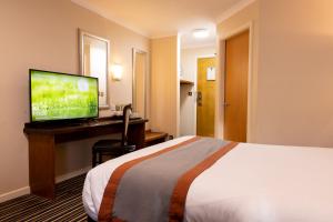 a hotel room with a bed and a desk with a television at Weathervane Hotel by Greene King Inns in Stoke on Trent