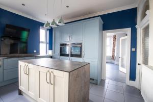 a kitchen with blue walls and a large island at Group Accommodation - Rushden A6 Manor House - Private Gated -Sleeps 15 - Secure Parking in Rushden +21 photos