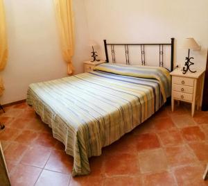 a bedroom with a bed with a striped bedspread and two night stands at Grazioso appartamento con tutti confort in Lu Lioni