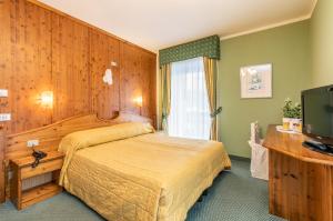 a hotel room with a bed and a television at G. Hotel Des Alpes (Classic since 1912) in San Martino di Castrozza
