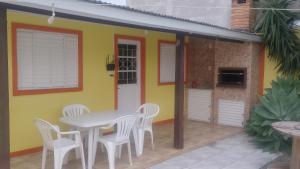 a table and chairs in front of a yellow house at Pousada Cabral in São Gabriel