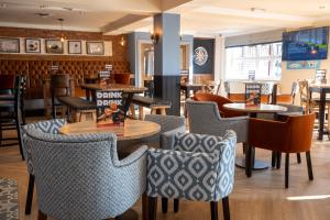 a dining room with tables and chairs in a restaurant at Weathervane Hotel by Greene King Inns in Stoke on Trent