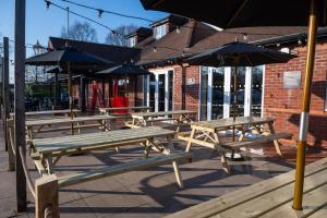 a group of picnic tables with umbrellas in front of a building at Weathervane Hotel by Greene King Inns in Stoke on Trent