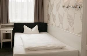 a white bed with a black headboard and white pillows at Aachener Stadthotel in Aachen