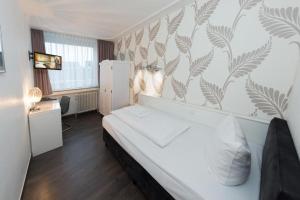 a bedroom with a white bed and a wall with plants at Aachener Stadthotel in Aachen