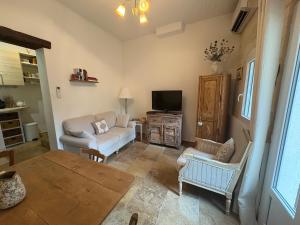 a living room with a couch and a tv at Chez Fabienne Maison Fontvieille in Fontvieille