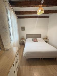 a bedroom with a white bed and two night stands at Chez Fabienne Maison Fontvieille in Fontvieille