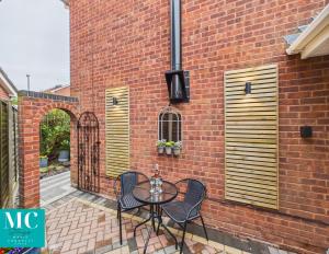a patio with a table and chairs next to a brick wall at The Cosy Retreat in Droitwich