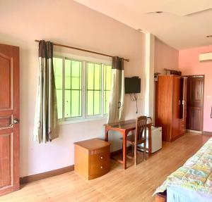 a bedroom with a desk and a bed and a window at สายป่านอาพาร์ทเม้นท์ in Ban Bung Sam Phan Nok
