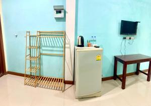 a blue room with a refrigerator and a table at สายป่านอาพาร์ทเม้นท์ in Ban Bung Sam Phan Nok