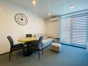 a living room with a couch and a table and a clock at Apartman Alex in Liptovský Mikuláš