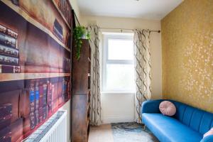 a living room with a blue couch and a window at Group Accommodation - Rushden A6 Manor House - Private Gated -Sleeps 15 - Secure Parking in Rushden
