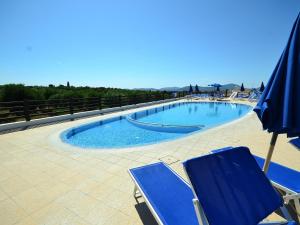 a swimming pool with blue chairs and an umbrella at Belvilla by OYO Vista Blu Resort Villa Otto Pax in Alghero