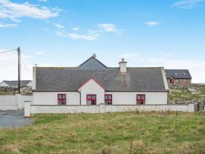 a white house with red windows on a field at 3 Bed in Roundstone oc-i234 in Callow