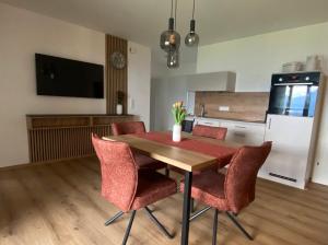 a kitchen with a wooden table with chairs and a refrigerator at Auszeit am Mondseeberg in Tiefgraben +5 photos