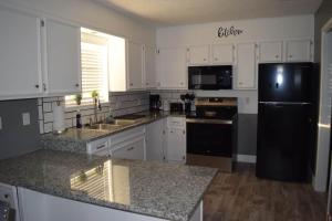 a kitchen with white cabinets and a black refrigerator at The Duplex in Lubbock