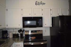 a kitchen with white cabinets and a black microwave at The Duplex in Lubbock