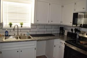 a kitchen with white cabinets and a sink at The Duplex in Lubbock +10 photos
