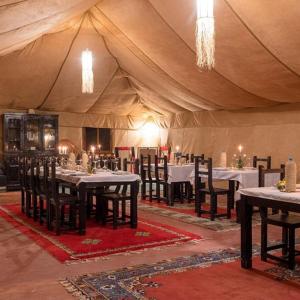 a dining room with tables and chairs in a tent at Overnight Luxury Camp in Merzouga