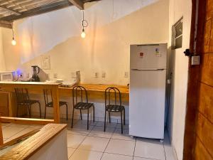a kitchen with a refrigerator and a counter with chairs at Hostel Mar in São Luís