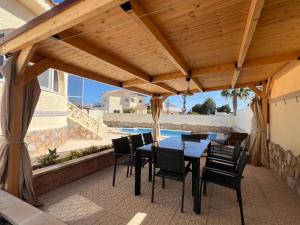 a patio with a table and chairs under a wooden roof at Casa Noel in Ciudad Quesada