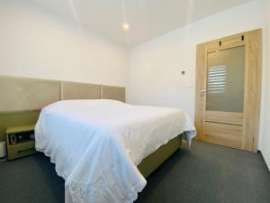 a bedroom with a white bed and a wooden door at Apartman Alex in Liptovský Mikuláš
