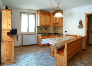 a kitchen with wooden cabinets and a table in it at Ca' Maria - Casa in Scalve in Schilpario +18 photos