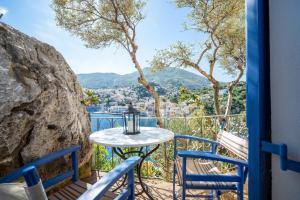 Ein Tisch und Stühle auf einem Balkon mit Blick auf die Stadt in der Unterkunft Artiki's Studios - Sea & Harbour View Apartments in Symi in Symi
