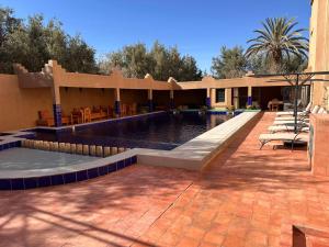 a swimming pool with chairs and a house at Kasbah Ait ben Damiette in Skoura