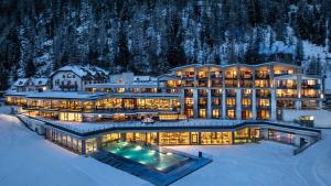 ein Hotel im Schnee mit eingeschalteten Lichtern in der Unterkunft Die Post am Ortler in Sulden