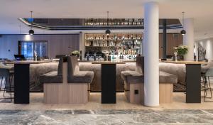 Eine Bar in der Lobby eines Hotels mit Hockern in der Unterkunft Die Post am Ortler in Sulden