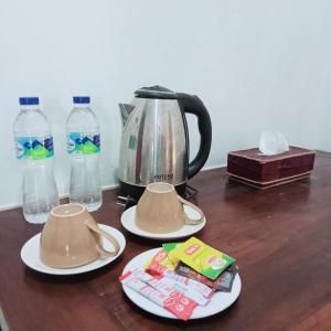 a tea pot and cups on a table with bottles of water at Palagan Boutique Hotel in Ngaglik