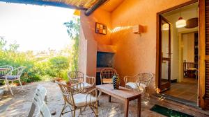 a patio with chairs and a wooden table and a table at Villa Averla-Costa Paradiso, con giardino vista graniti e mare in Costa Paradiso