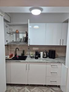 a kitchen with white cabinets and a sink at studiou central in Târgu Jiu +4 photos