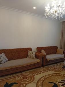 a living room with two couches and a chandelier at Shahdag Beloved Home in Qusar