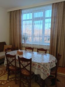 a dining room table with chairs and a large window at Shahdag Beloved Home in Qusar