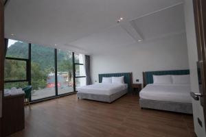 a bedroom with two beds and a large window at Ha Giang Numa Hotel in Ha Giang