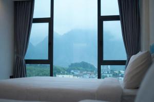 a bedroom with a bed and a large window at Ha Giang Numa Hotel in Ha Giang