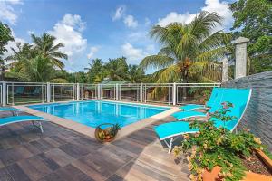 a swimming pool with blue chairs on a patio at Gîte Dalina Sainte-Rose in Sainte-Rose