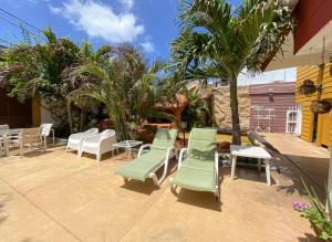 a patio with chairs and tables and palm trees at Hospedaje Solymar Sarie Bay in San Andrés