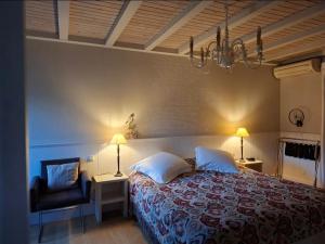 a bedroom with a bed and a chair and a chandelier at B&B Kerkevelde in Bilzen