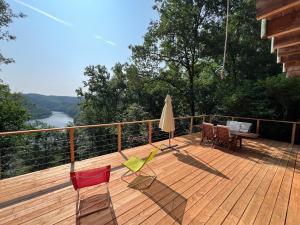 a wooden deck with chairs and an umbrella at Chalet vue lac in Miremont