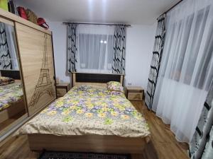 a bedroom with a bed with a floral comforter at Cabana Acasă la Delia in Gârda de Sus