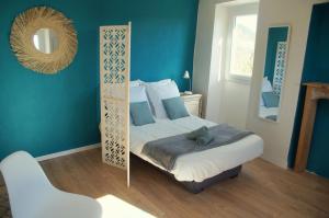 a bedroom with blue walls and a bed with a mirror at Le Mazet d'Aurore in Chassiers