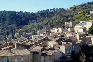 a village on a hill with houses and trees at Le Mazet d'Aurore in Chassiers
