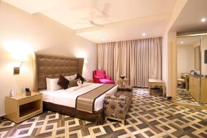 ein Hotelzimmer mit einem großen Bett und einem Stuhl in der Unterkunft Best Western Ashoka in Hyderabad + 79 Fotos